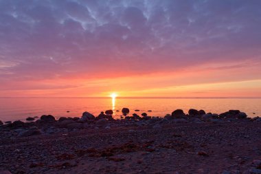 Finlandiya 'nın Kemionsaari adasında ilkbaharda kayalık deniz kıyısında renkli bir günbatımı.
