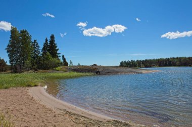 Yazın gökyüzünde bulutlar olan kumlu sahil manzaralı Lovo, Finlandiya.