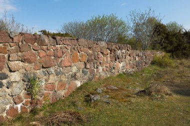 Çimenli eski taş duvar ve güneşli bahar havasında yapraksız ağaçlar. .