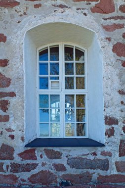 Taş bir duvarda kemer olan beyaz çerçeveli pencereye yakın çekim.