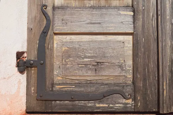 Closeup of an old iron door hinge on a weathered wood door.