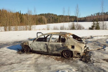 Yol kenarında yangın hasarı olan yanmış bir araba..
