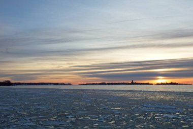 Kışın Hernesaari 'den deniz buzu ve suyla birlikte bulutlu günbatımı manzarası, Helsinki, Finlandiya.