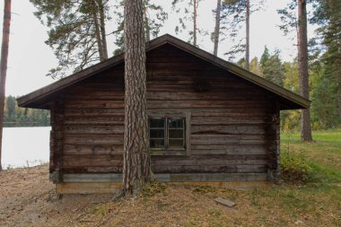 Gölün kıyısındaki eski ahşap kulübe Bulutlu sonbahar havasında.