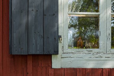 Beyaz ahşap çerçeveli eski pencerenin ve kırmızı ahşap duvarlı siyah panjurların kapatılması..