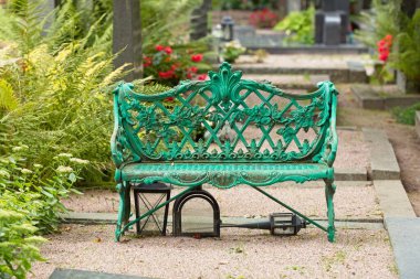 Mezarlıktaki eski yeşil metal park bankında..