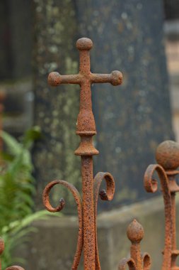 Mezarlıktaki çitlerin üzerinde paslı metal haç var..