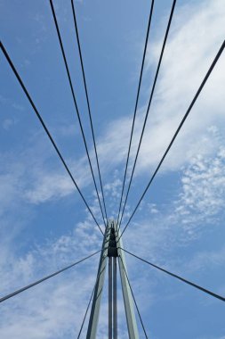 Yazın gökyüzünde bulutlar olan köprü kablolarının soyut görüntüsü.