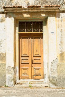 Eski, yıpranmış çift kapılı taş bir bina.