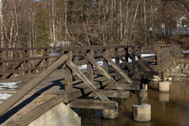 Nehrin üzerinde tahta köprü, yerde az kar var. Nad nehri kışın donmuyor, Pickala, Finlandiya..