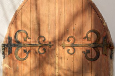Decorative rustic metal hinges on old wooden doors on a stone building. clipart