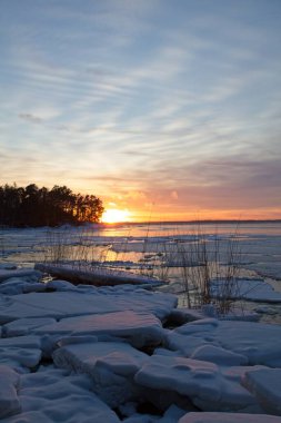 Kışın gün batımında denizde buz kütlesi ve gökyüzünde bulutlar, Mussalo, Kotka, Finlandiya.
