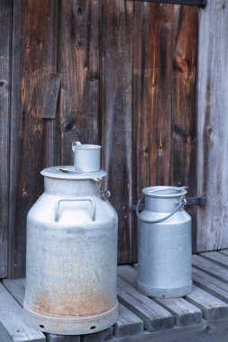 Kırsal kesimdeki eski ahşap tahtaların üzerindeki eski tip alüminyum süt kutusuna yakın çekim.