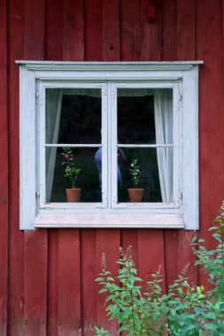 Kırmızı bir hava durumu duvarında beyaz çerçeveli pencere.