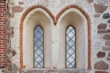 Taş ve tuğladan yapılmış dekoratif eski bir binanın ahşap çerçeveli pencereleri..