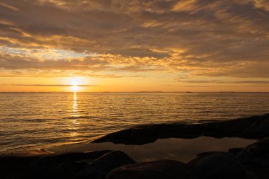 Yazın deniz aşırı sarı gün batımı ve kayalar üzerinde gölet, Jungfruskr, Archipelago Ulusal Parkı, Finlandiya.