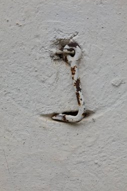 Eski metal kapı kancası beyaz alçılı bir duvara asılı..