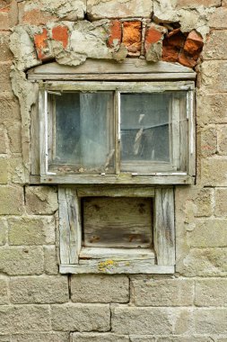 Terk edilmiş bir taş binanın ahşap çerçeveli penceresi..