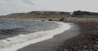 Yazın Hamningberg 'e giden 8100 nolu yoldaki kayalık bir plaja vuran dalgalar, Varanger Yarımadası, Norveç.