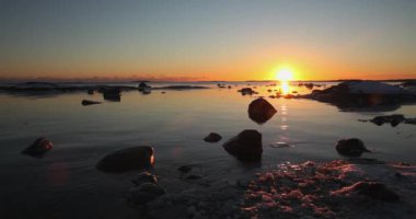 Kışın açık deniz kıyısında gün batımı ve kaya silueti Lauttasaari, Helsinki, Finlandiya.