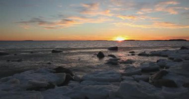 Kışın açık deniz kıyısında gün batımı ve kaya silueti Lauttasaari, Helsinki, Finlandiya.