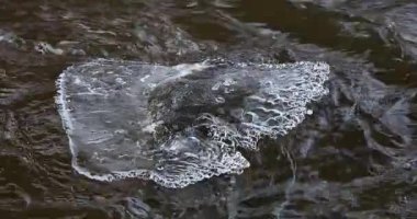 Akmakta olan nehirde kışın donmuş buzla birlikte kayalar..