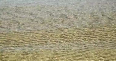 Yaz günü su yüzeyinde dalgalı altın kum.