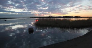 Günbatımında deniz kıyısı, sonbaharda deniz yüzeyine yansıyan gökyüzü ile, Kallahti, Helsinki, Finlandiya.