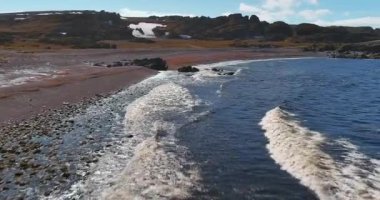 Havadan Hamningberg 'e giden 8100 nolu yol boyunca uzanan kıyı şeridi Barents Denizi' nden kayalık plaja vuran dalgalar güneşli yaz havası, Varanger Yarımadası, Norveç.