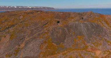 Kongsfjord 'da Barents Denizi kıyısında güneşli yaz mevsiminde 890 nolu yol boyunca uzanan bir şapkanın havadan görünüşü, Varanger Yarımadası, Norveç.