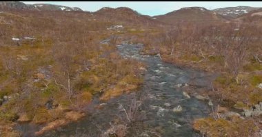 Norveç 'in güneşli bahar havasında E6 (Bugoyfjordveien) yolu boyunca akan bir nehrin havadan görünüşü.