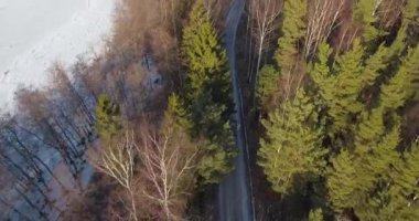 Kışın çakıl yolu ile tepeden aşağı manzaralı orman ağaçlarının havadan görünüşü, Kopparnas, Finlandiya.