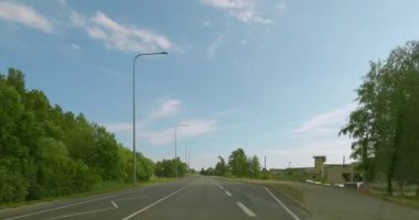 Virtsu, Estonya - 6.26.2023: Virtsu şehrinde yaz aylarında gökyüzünde bulutlar varken araba sürerken POV görüntüsü.