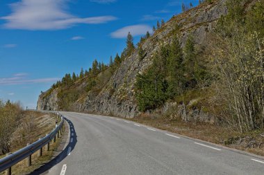 Svanvikveien Yolu (8850) güneşli bahar havasında gökyüzü bulutlu, Norveç.