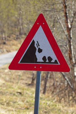 Beyaz zemine düşen kayaları gösteren kırmızı bir üçgen tabela..