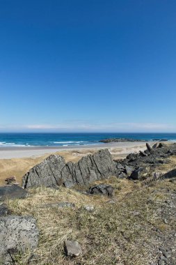 View of rock and sand beach at Sandfjorden in sunny summer weather, Varanger Peninsula, Norway. clipart