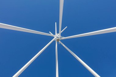 Mavi gökyüzüne karşı beyaz boyanmış metal direklerin soyut görüntüsü.