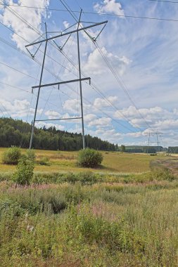 Bulutlu bir yaz gününde direkler ve elektrik hatları.