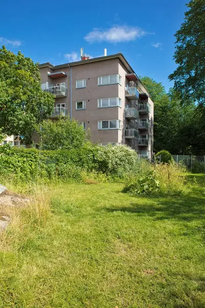 Yazın ağaçlarla çevrili eski beton apartman..