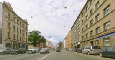 Riga, Latvia - July 9.2023 : POV view from car driving in Riga city on a asphalt road in summer with clouds in the sky.