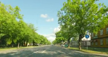 Parnu, Estonia - July 8.2023 : POV view from car driving in Parnu city on a asphalt road in summer with clouds in the sky.