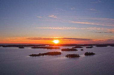 Gökyüzünde bulutlar, Kallahdenniemi, Helsinki, Finlandiya 'da kışın deniz ve adaların üzerinde gün batımını gösteren hava manzarası.