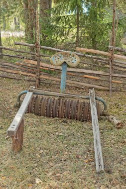 Ahşap çitin yanındaki tarlada tarım için eski paslı metal tarım ekipmanları ve uzun zamandır orada oturuyor..
