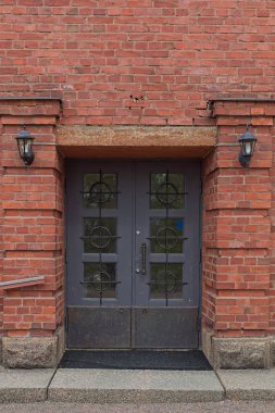 Kırmızı tuğlalı duvarda cam pencereleri olan eski mavi çift kapılı.