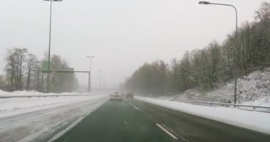 Turunvayla otoyolunda araba sürerken POV manzarası bulutlu kış havasında yerde kar varken, Espoo, Finlandiya.