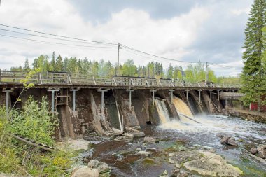 Virojoki nehri üzerindeki eski beton baraj bulutlu bir bahar gününde akan suyla, Virolahti, Finlandiya.