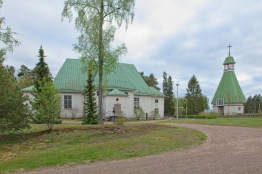 Eski ahşap Virolahti kilisesi ve bulutlu bahar havasında çan kulesi Virolahden kirkonkyla, Finlandiya.