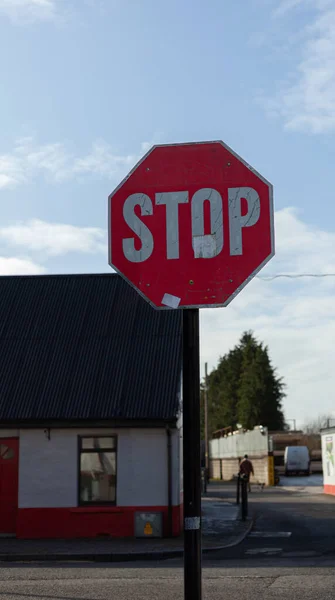 Stop sign on the street with a building and a small lane behind it in Ireland