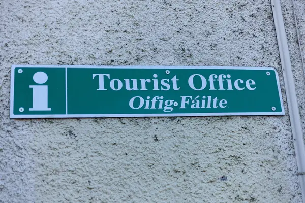 Green tourist office sign on a white wall