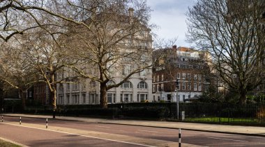 Kuşkafesi Yolu 'ndaki ağaçların arkasındaki beyaz bina Buckingham Sarayı' nın yanında, Londra 'daki St. James Park' ın yanında..